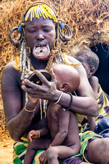 Ethiopia, a woman from the Mursi tribe with beautiful head decoration sits in front of her hut. Omo Valley, 
Jinka, 21th of february 2024
