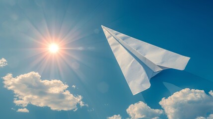   A paper plane flies against a backdrop of a radiant blue sky, with the sun casting long shadows and clouds scattered before it