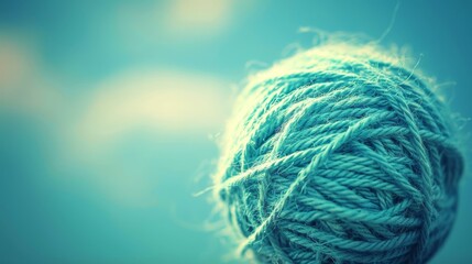   A blue yarn ball sits atop a wooden table against a backdrop of a blue-and-white sky adorned with clouds - obrazy, fototapety, plakaty