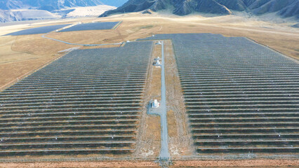 Aerial view of a large of solar panels on plateau in mountainous desert. Generates environmentally friendly energy at a power plant station. Alternative energy sources, green energy