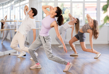 Group of men and women dance an energetic hip-hop dance in a studio. Modern dance lesson