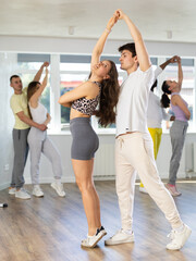 Young man and young woman dance ballroom dance waltz in studio