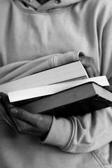 3 books held in the hands of a woman in a sports sweatshirt