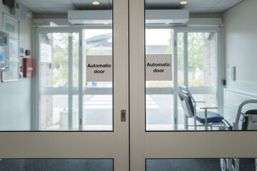 Automatic doors seen at the exit of an NHS outpatients department in a busy British hospital....