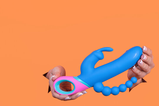 A sex toy. Vibrator on an orange background. Leisure for adults. Copy space