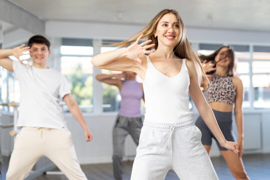 Group of men and women in sportswear dancing hip hop in dance studio
