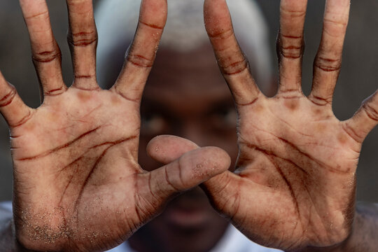 A captivating close-up of a man with sandy palms framing his intense gaze, highlighting the unique lines and textures of his skin