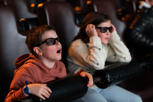 Excited kids wearing 3D glasses in movie theater