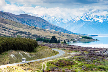 RV driving near mountains and lake in remote landscape