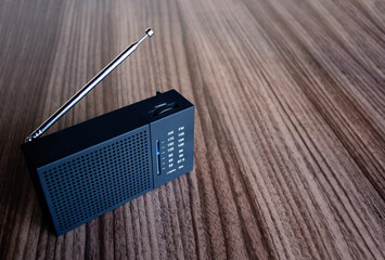 small portable radio sits on a wooden surface, copy space