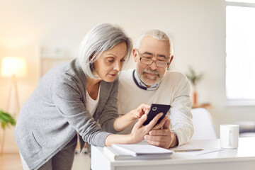 Smartphone usage among older adults, senior couple learn interacting with phone digital information online, nice elderly people, old pair family at home together, keep in touch with family and friends
