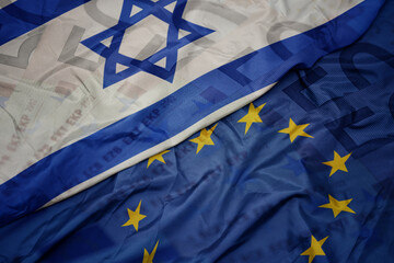 waving colorful flag of european union and flag of israel on a euro money banknotes background. finance concept.