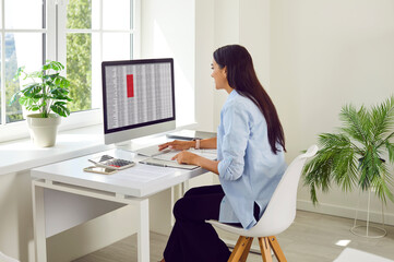 Whether in a home office or traditional workspace, a dedicated businesswoman or accountant working. With a desktop computer, she seamlessly integrates paperwork and digital online technology. - 796959609