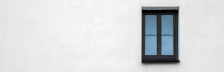 White wall of the house with a small window. Lonely window on the white wall of the building. View of a fragment of a wall with one window. Lonely window on the white wall of the house.