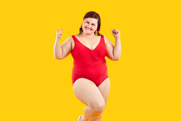 Happy plus size female fashion model in swimwear. Studio shot of cheerful positive young fat woman...