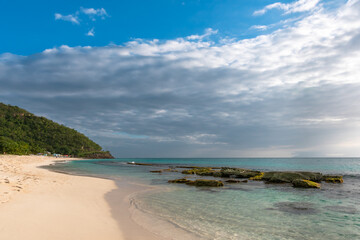 Scenic view of a tropical beach, white sand turquoise water with rocks in ocean