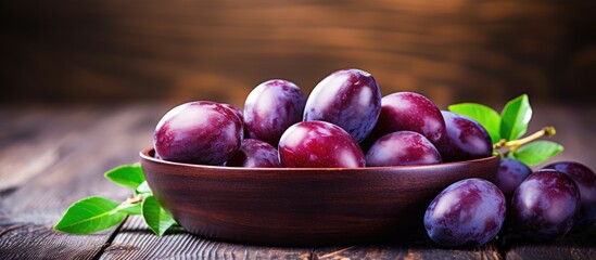 Bowl of ripe plums on rustic wooden table