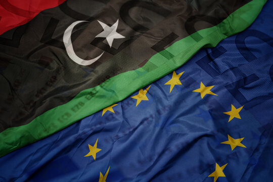 waving colorful flag of european union and flag of libya on a euro money banknotes background. finance concept.
