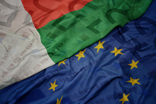 waving colorful flag of european union and flag of madagascar on a euro money banknotes background. finance concept.
