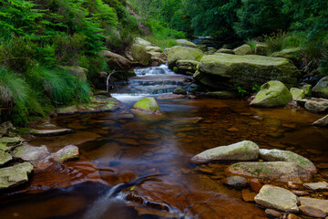 Water streaming over rocky cascades, Deep forest waterfall small waterfall with blurred water on the rocks in the peak district uk