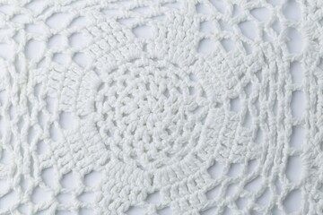 A white crocheted piece of fabric with a pattern of a flower. The flower is made up of many small...