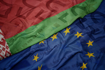 waving colorful flag of european union and flag of belarus on a euro money banknotes background....
