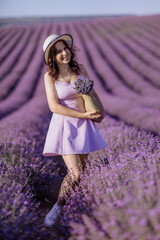 A woman is standing in a field of purple flowers, wearing a white hat and a purple dress. She is holding a bouquet of flowers in her hand. Concept of serenity and beauty.