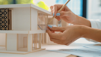 Closeup image of young beautiful caucasian architect engineer hand measure house length model by...
