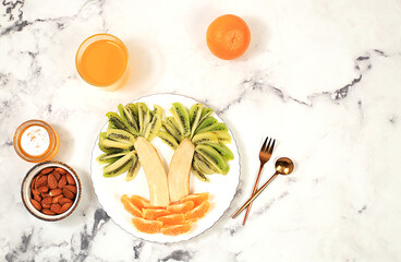 Healthy breakfast with ingredients, fun food for children, ideas for dish decoration, Healthy and natural food concept. Bananas, oranges and nuts in the form of palm trees