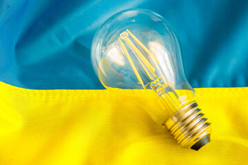 A glowing light bulb lying in the middle of the Ukrainian flag, Concept, Energy problems and energy...