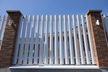 Modern white picket fence with brick posts