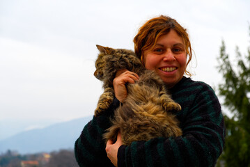 brunette fifty aged caucasian woman with green striped mallet cuddles a cat