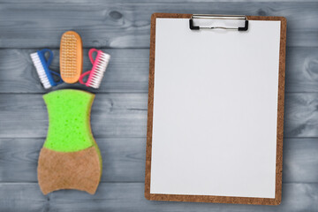 Clipboard with blank white page against background of composition of household and kitchen cleaning products. Place for text or design. selective focus. Kitchen cleaning tips