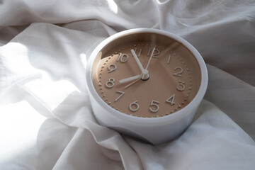 Alarm clock in bed with white blanket, top view, early rise concept, insomnia, daily routine and...