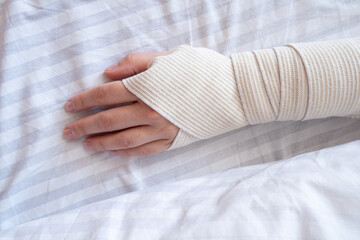 Young woman with bandaged hand on white background.  Health concept