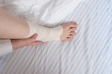 Woman touching her ankle with an elastic bandage, close-up video, sprain fracture. Health concept