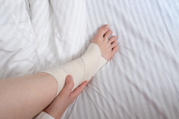 Woman touching her ankle with an elastic bandage, close-up video, sprain fracture. Health concept