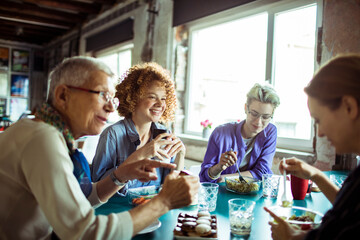 Diverse group of women of different age eating lunch at office