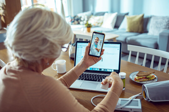 Elderly woman in telehealth session with doctor on smartphone at home