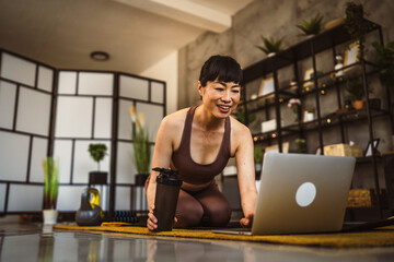 Mature japanese woman exercise at home watch the training on the laptop