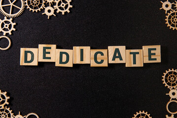 Word Dedicate on a row of wooden blocks. Devotion dedication love concept.