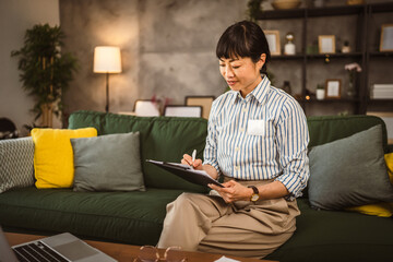 Mature japanese woman read document on clipboard and work from home