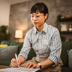 Mature japanese woman with eyeglasses work from home and sign document