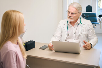 Lady patient consulting with male doctor in clinic office - 797059270