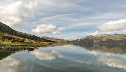 
Nearby lagoon with wooden furniture and distant mountains with forests, cloudy sky in Acomayo,...