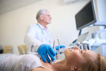 Woman getting thyroid ultrasound exam in hospital - 797065036