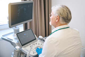 Medical specialist making ultrasonic diagnostics in hospital