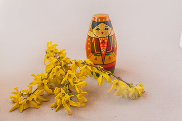 Souvenir stylized as a Tatar girl next to flowering branches of forsythia  on a gray background. Mass production. Navruz holiday concept