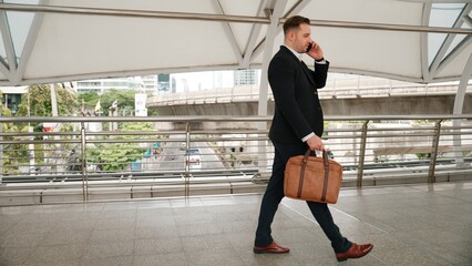 Smart caucasian businessman calling his colleague to plan financial strategy while walking to...