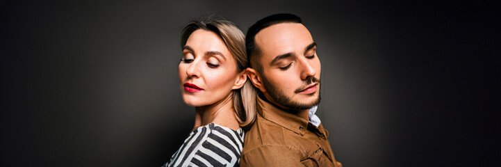 young couple back to back with eyes closed in a studio